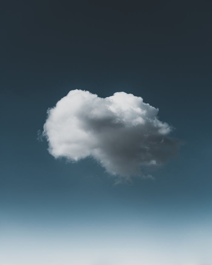 A single fluffy cloud floating in a clear, bright blue sky. Ideal for backgrounds.